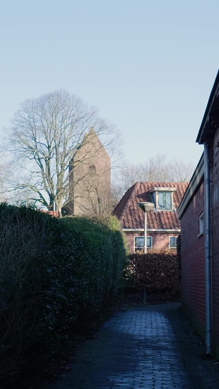 Narrow Cobblestone Alleyway Leading to a Church Tower and Residential Houses