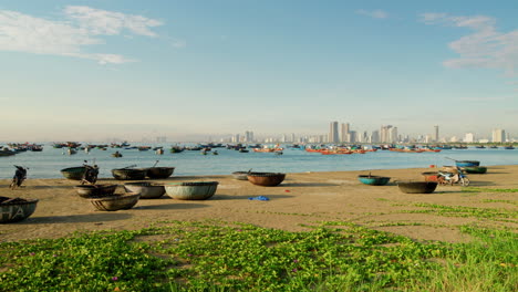 static establishing shot of traditional vietnamese round bamboo basket boats on shore and fishermen in water off da nang