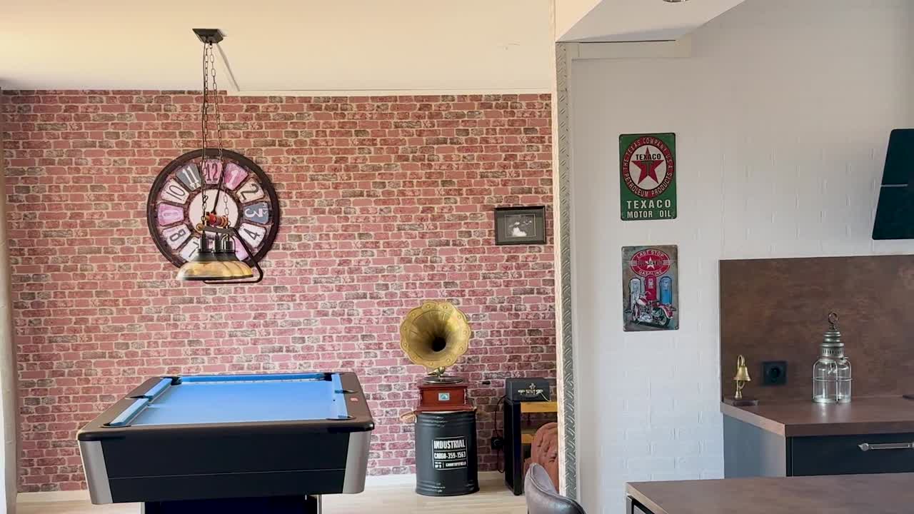 A stylish interior featuring a blue pool table against a red brick accent wall