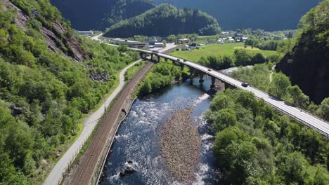 Road-E16-crossing-concrete-bridge-over-Dalekvam-river-between-Bergen-and-Voss---Railroad-between-Bergen-and-Oslo-on-left-side---Aerial-Norway