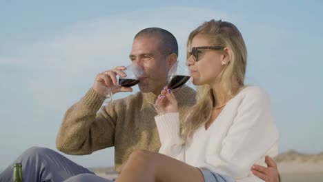 happy caucasian couple drinking wine at seashore.