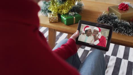 Kaukasischer-Mann-Winkt-Und-Nutzt-Tablet-Für-Weihnachtsvideoanruf-Mit-Lächelndem-Paar-Auf-Dem-Bildschirm