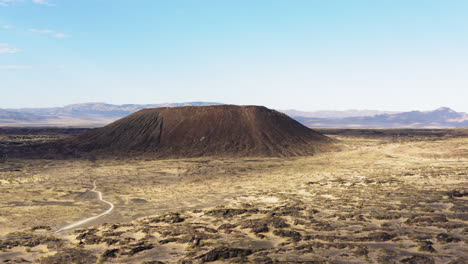 Aerial-view-approaching-volcanic-Amboy-Crater-in-the-Mojave-Desert-from-a-distance