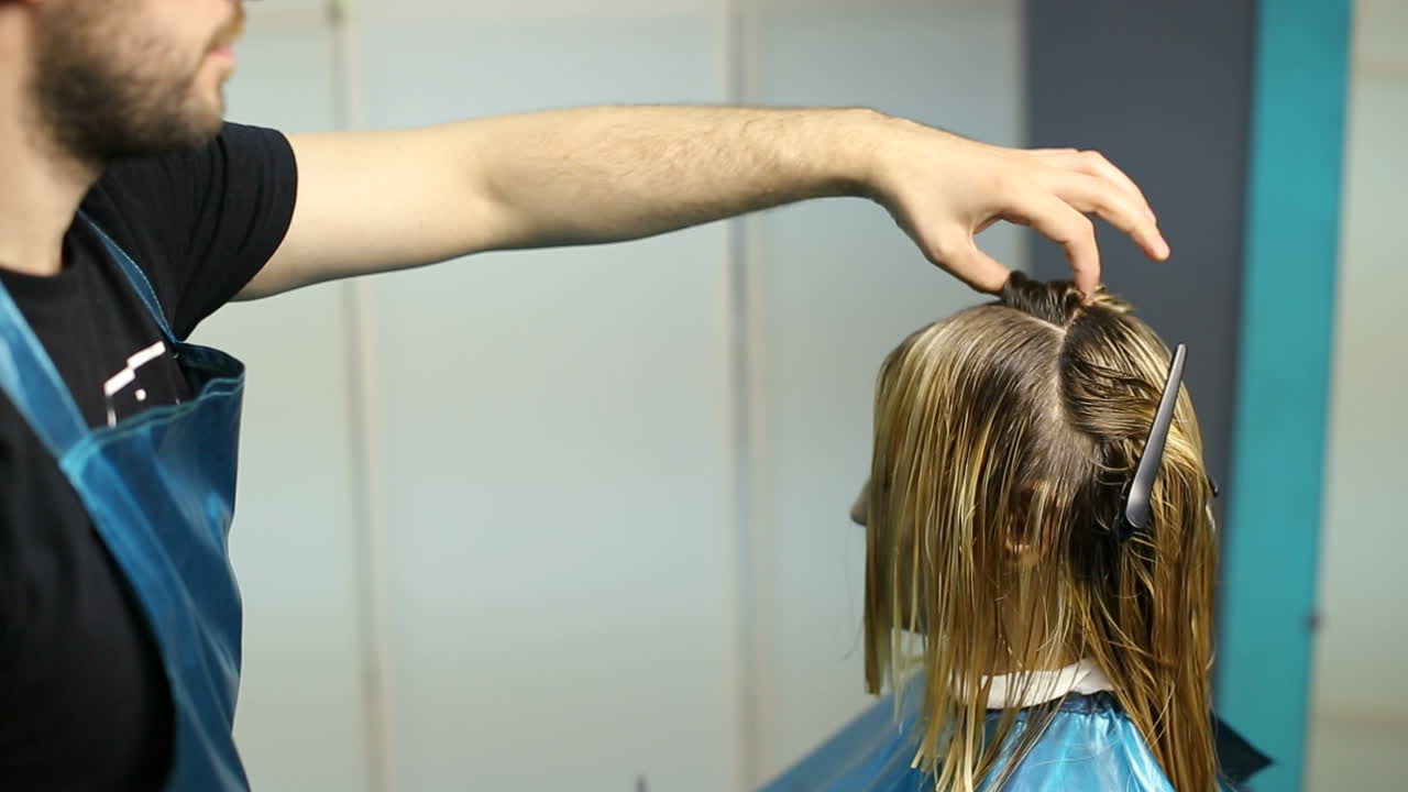 Young woman with hairdresser cutting hair at salon