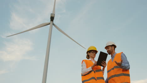 lower view of two caucasian male and female engineers discussing some problems and reading a documento at the wind station of renewable energy