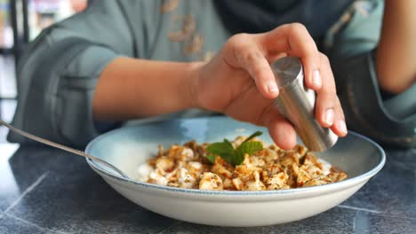 mujer añadiendo sal y pimienta a un plato de manti turco