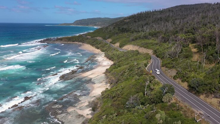 Un autobus e un fuoristrada percorrono la famosa Great Ocean Road australiana, Victoria.