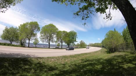 timelapse at a waterfont on a blye sky day with many cyclists and cars going by really fast