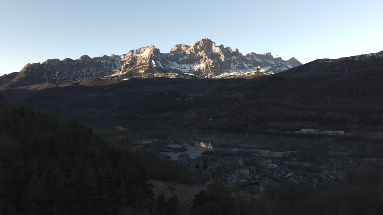 Paysage montagneux avec village et lac au lever/coucher du soleil