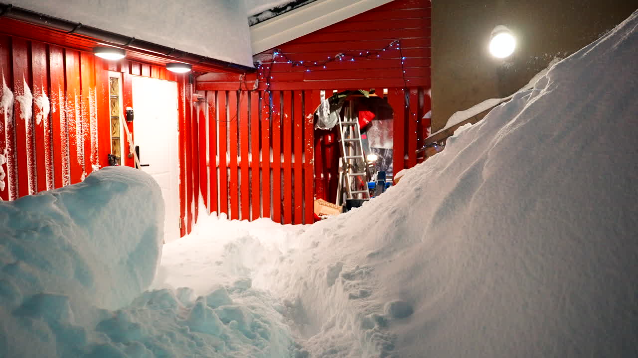 Heavy snowfall, ladder, red wooden shed building, warm exterior lights