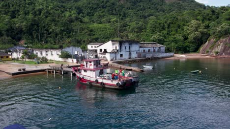 workers loading trash in garbage boat anchored at ilha grande island, rio de janeiro, brazil