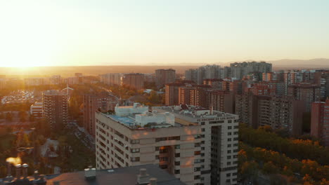 Fly-over-roof-of-apartment-building-on-large-housing-estate.-View-against-setting-sun.