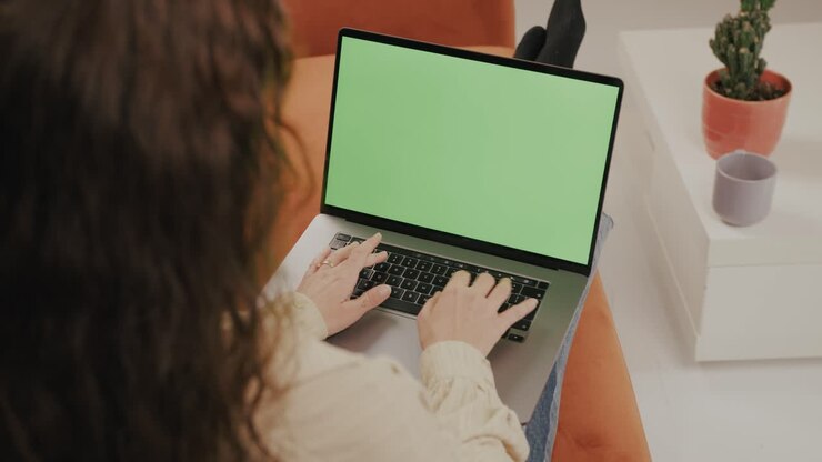 Ung kvinde arbejder hjemmefra på sin bærbare computer, mens hun sidder komfortabelt på en sofa.