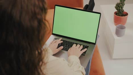 young woman is working from home on her laptop, while comfortably sitting on a couch