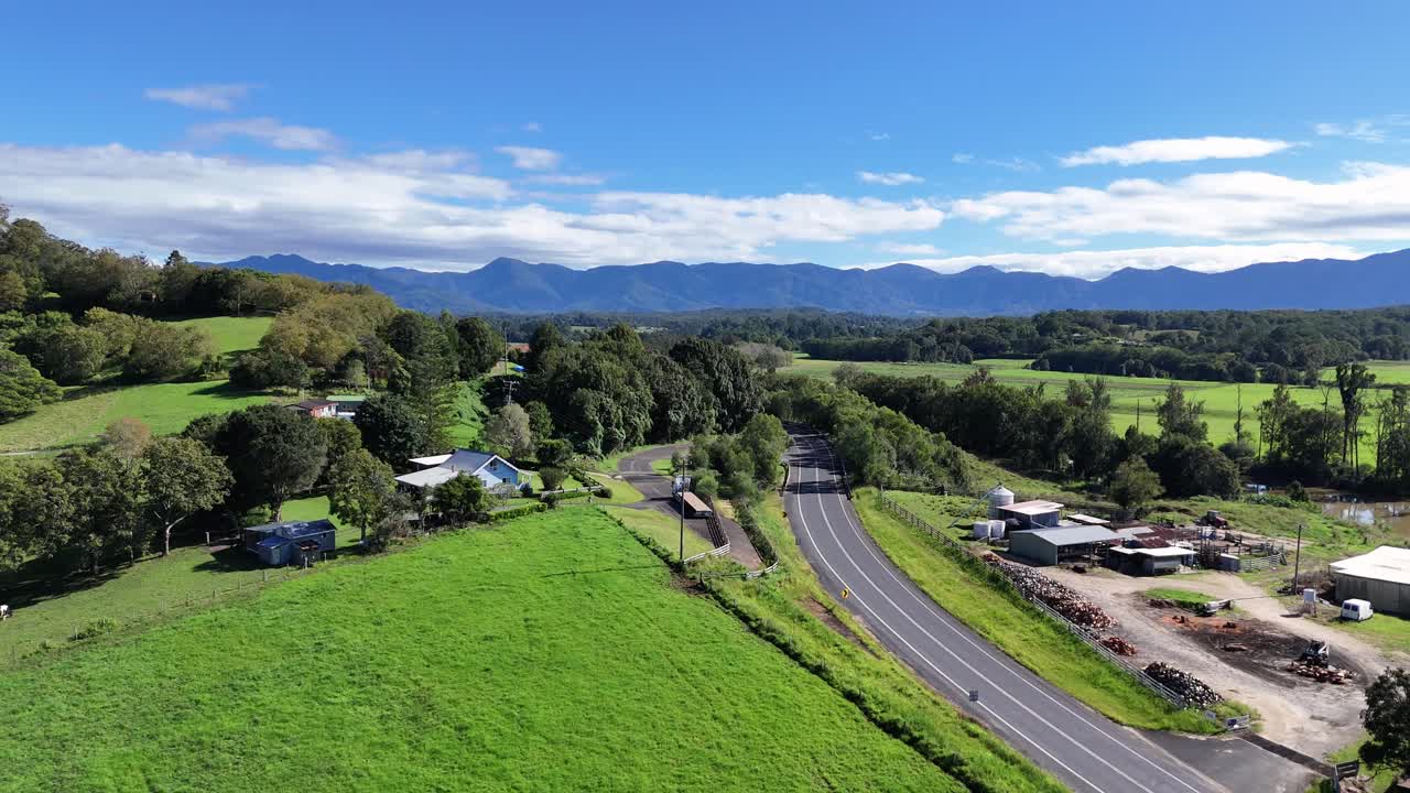 Aerial footage captures lush green fields and winding roads under clear blue skies in Bellingen, NSW, Australia
