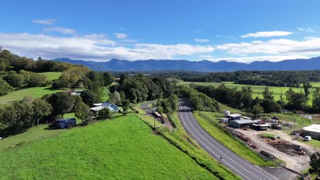 aerial footage captures lush green fields and winding roads under clear blue skies in bellingen, nsw, australia