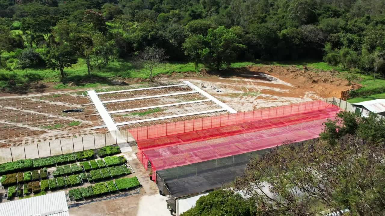 Aerial flying forward over beautiful landscape revealing greenhouse and plantation