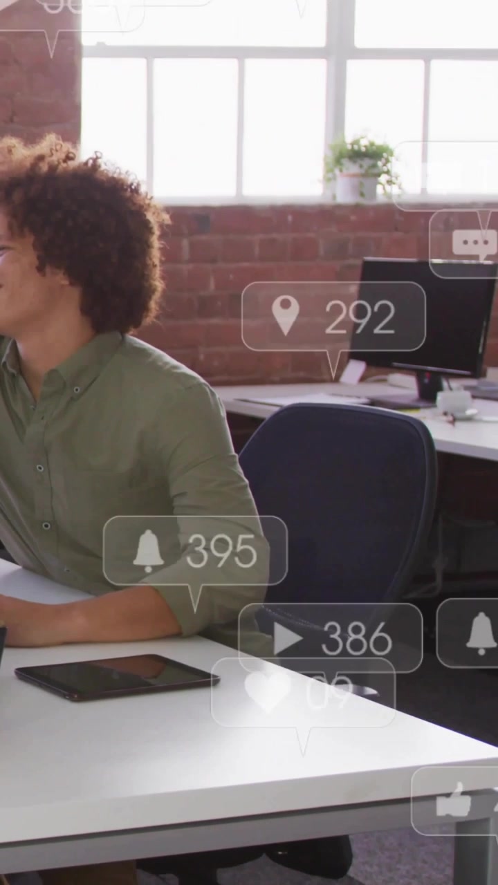 Vertical video: Man at desk seeing floating alerts tapping tablet viewing engagement for marketing
