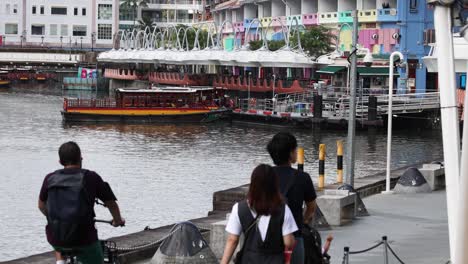 cyclists and pedestrians observe passing boat.