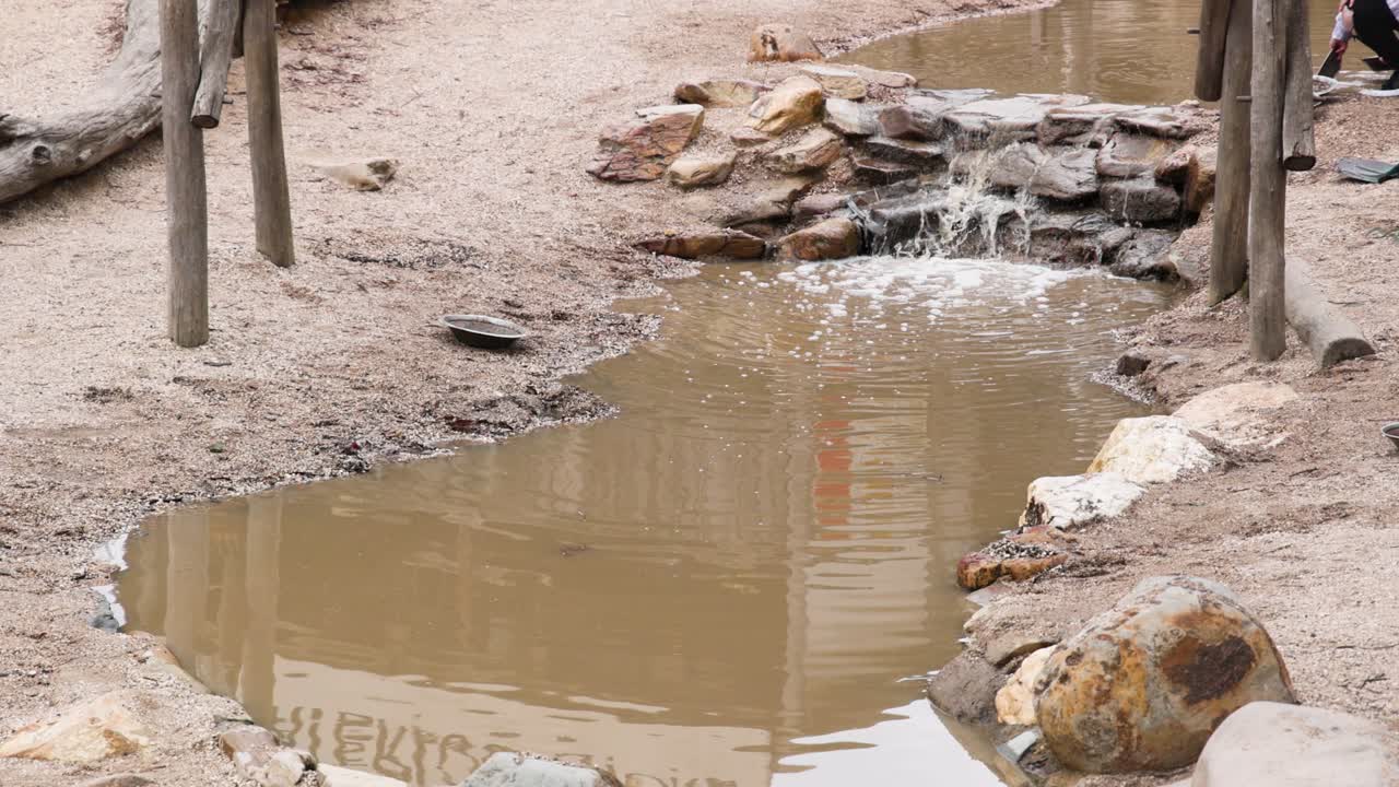 pequeña cascada que desemboca en un arroyo fangoso