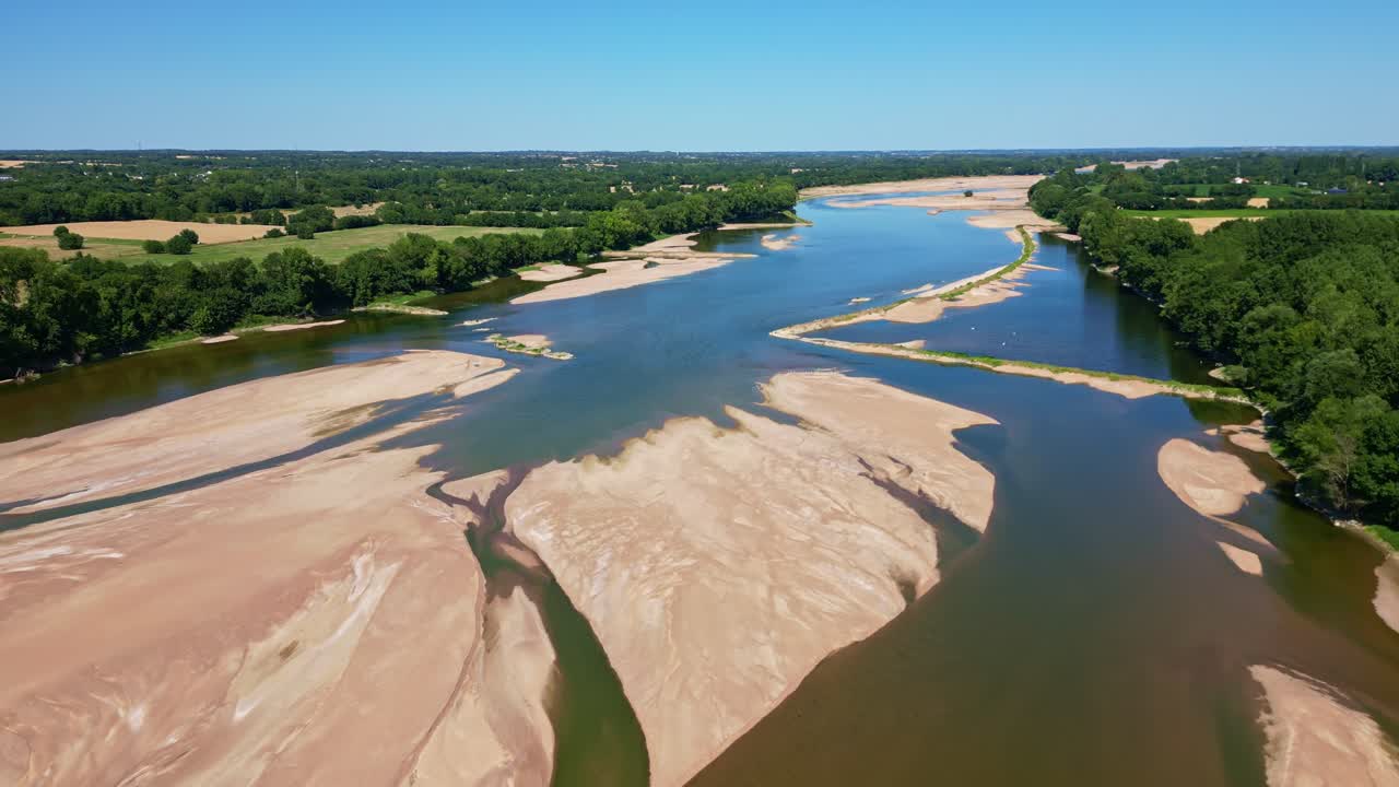 Loire River with sandbanks, green forest on riverbanks under clear blue sky, Loireauxence, France. Aerial drone forward