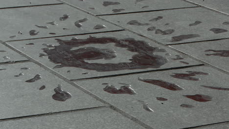 close up view of man walking over sarajevo rose, a war memorial on the street indicating where three or more people were killed during the siege of sarajevo, bosnia.