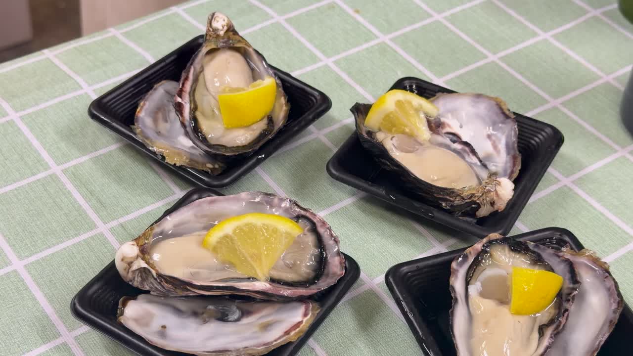 High angle shot of four fresh raw oysters served with lemon on a checkered tablecloth