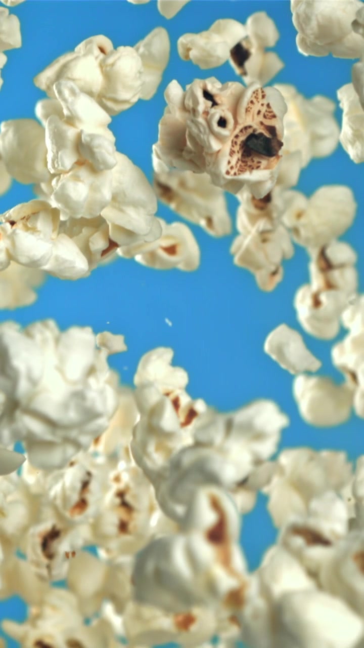 Popcorn che cadono al rallentatore su un vivace sfondo blu