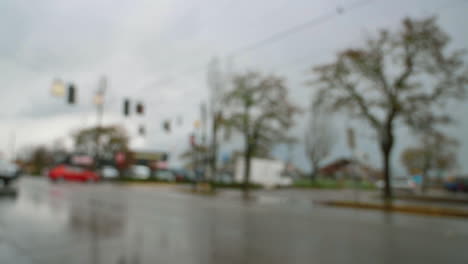 defocused white van turn from corner on wet asphalt city road intersection under gloomy sky