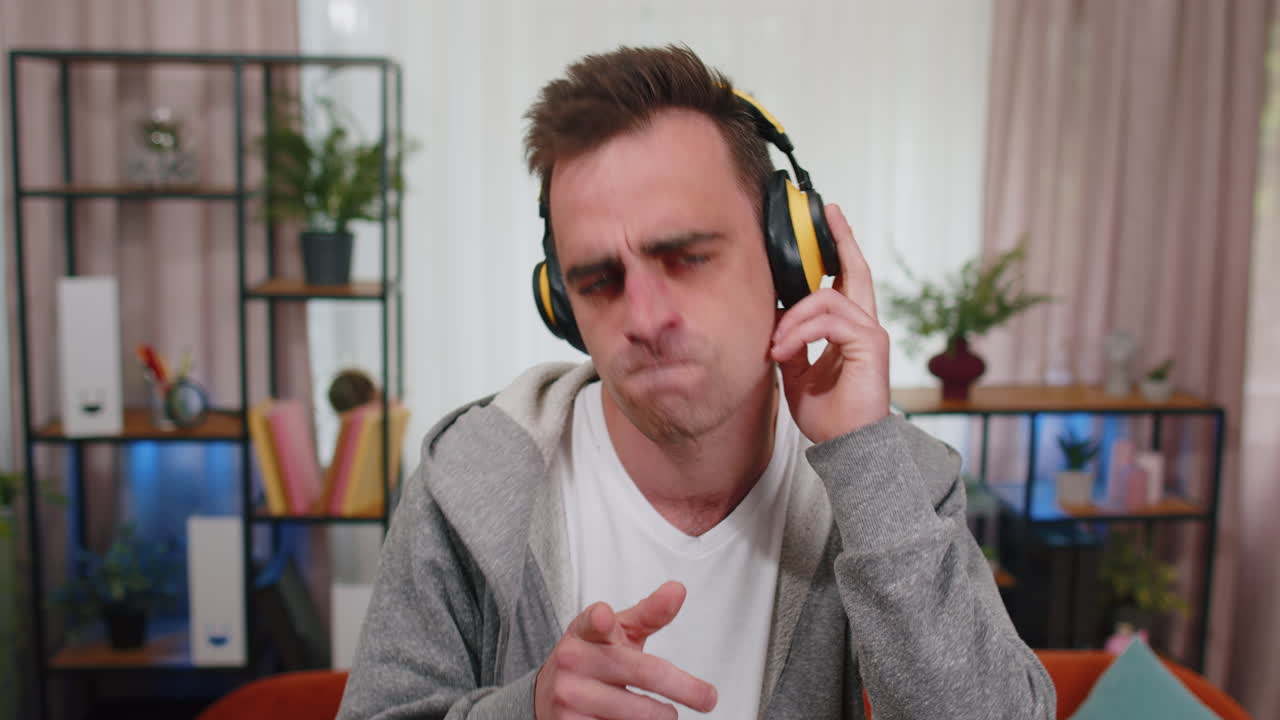 joven adulto feliz con auriculares inalámbricos bailando cantando escuchando la canción favorita en la habitación en casa