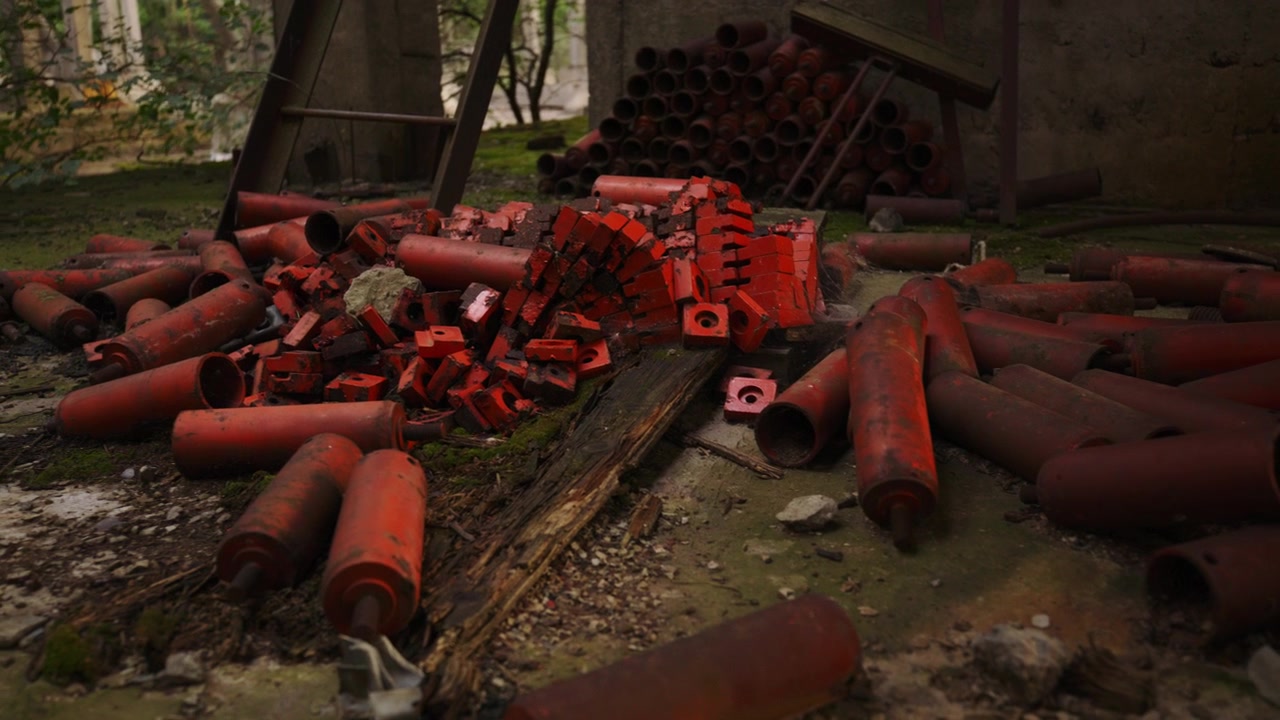 Rusted industrial metal components lie abandoned on a mossy concrete floor.