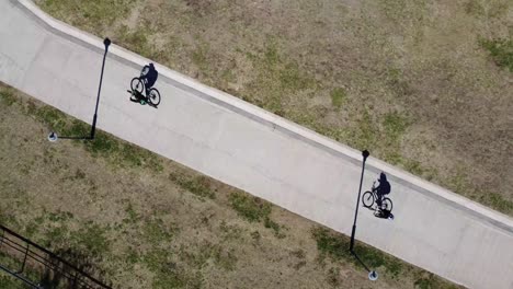 aerial footage of two cyclists on an asphalt road