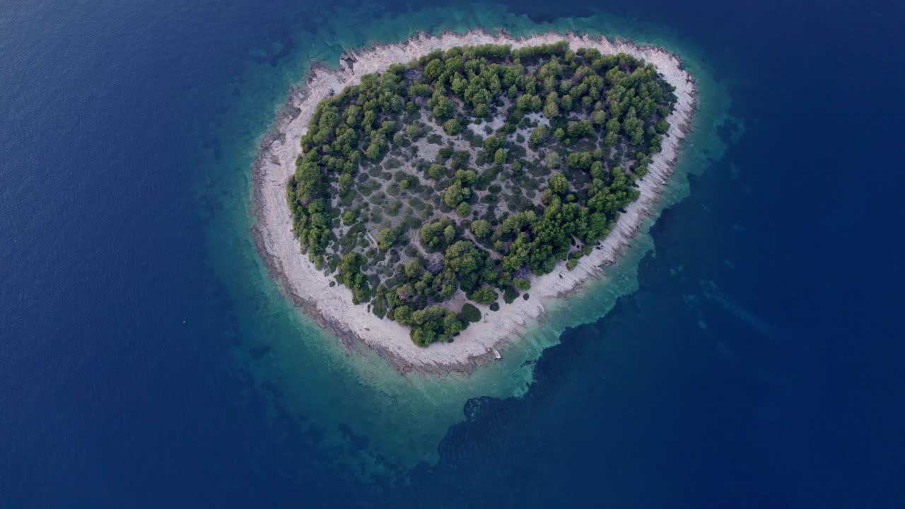 Drohnenaufnahme einer ruhigen Insel, umgeben von klarem Wasser und üppigem Grün