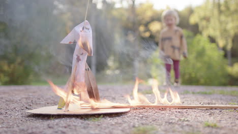 Toddler-looks-on-as-rocket-launch-experiment-fails-and-burns-out,-low-angle