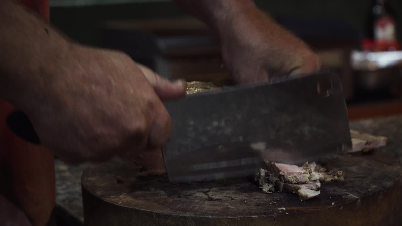 Indian food court in Vietnam. Person slicing meat using a meat cleaver. Close up locked off shot