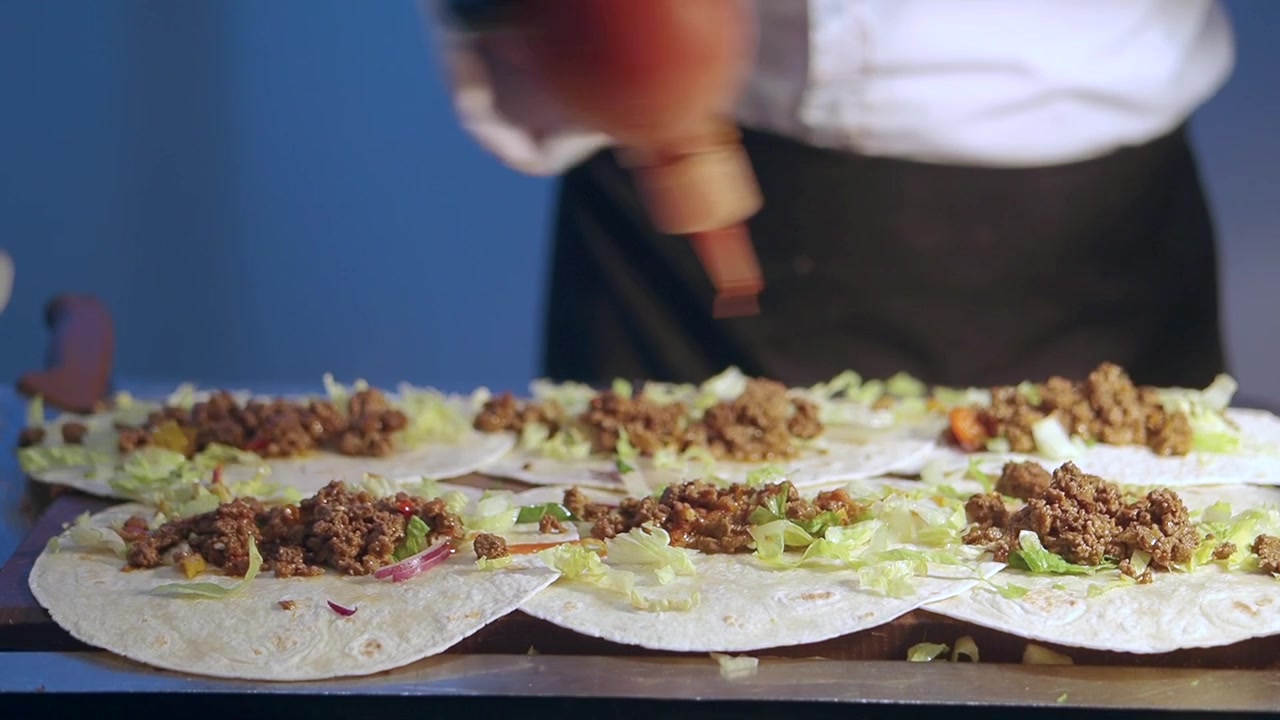 Kok tilbereder tacos med hakket kød og friske grøntsager