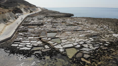 an aerial drone shot slowly ascending to reveal the scope of the ancient gozo salt pans in malta