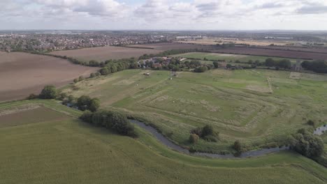 Aerial-pan-shot-of-fields-and-farms-with-a-river-cutting-through-them