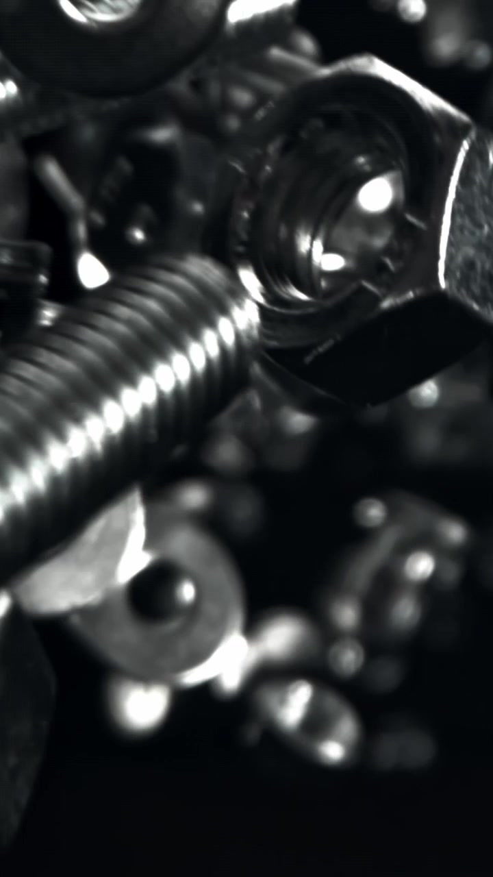 Elementi di Fissaggio Metallici che Cadono al Rallentatore su Sfondo Nero