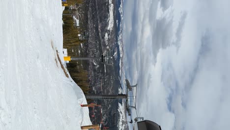 ski lift carrying skiers and snowboarders to the top of a ski run on an overcast day, vertical