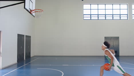 young biracial man plays basketball indoors, with copy space