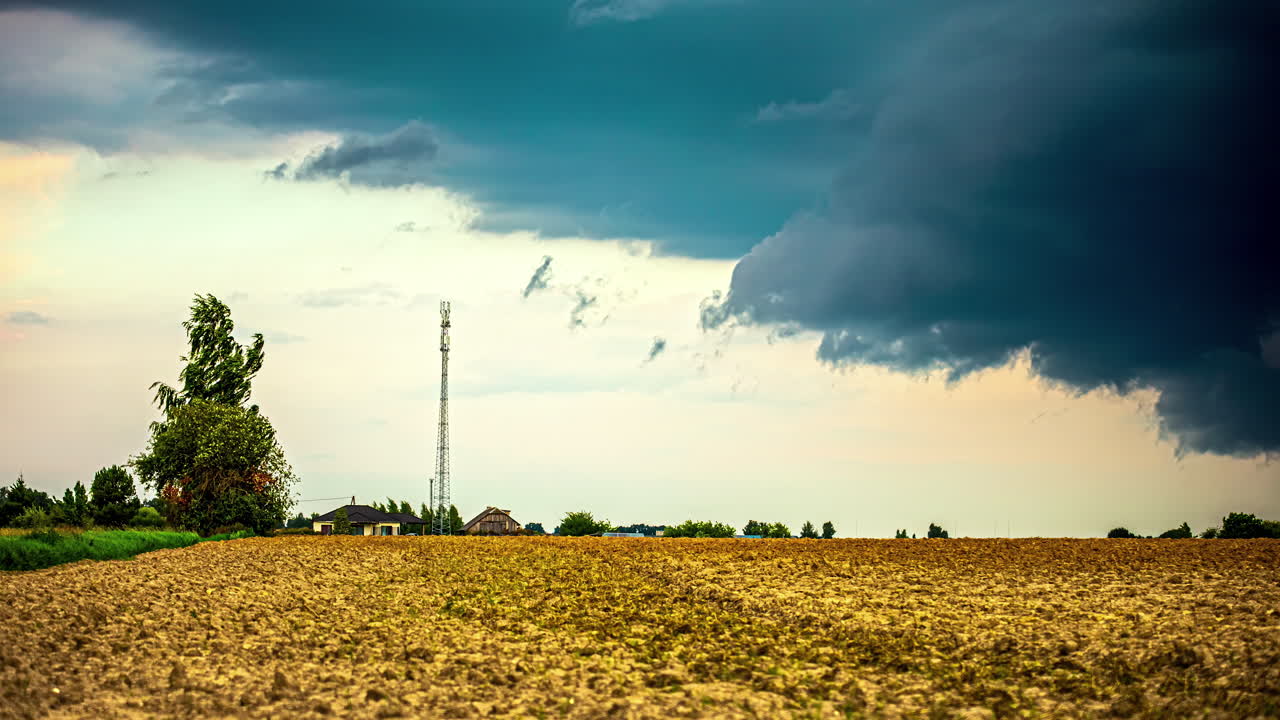 временный снимок приближающегося шторма, когда облака собираются над ландшафтом или полем и становятся черными в поле с видом электрического столба на заднем плане