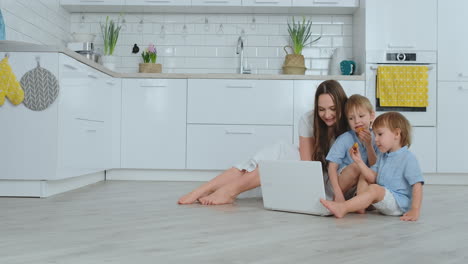 beautiful modern young family lying on the floor at home and doing something in laptop