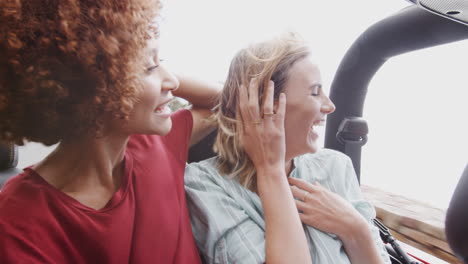 group of young friends in back of open top hire car on summer vacation