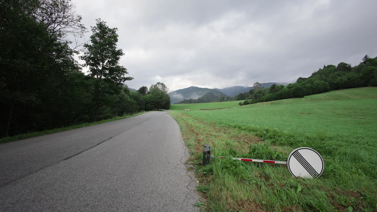 흐린 날 잔디에 누워있는 국가 속도 제한 표지판과 함께 시골 도로를 가로지르는 돌리 팬