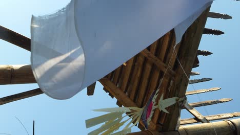 Vertical-slow-motion-shot-from-a-viewpoint-at-a-temple-with-religious-hindu-elements-a-dreamcatcher-and-white-cloth-blowing-in-the-wind-during-a-bali-trip-through-indonesia