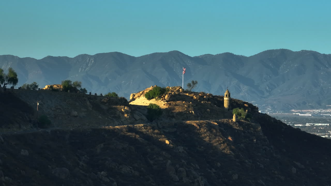 Aerial view around the castle and US flag on top of mount Rubidoux, sunset in USA