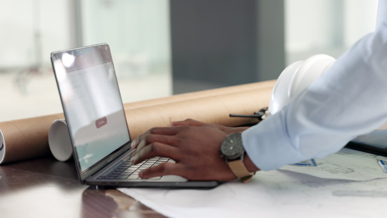 ingeniero trabajando en una computadora portátil con planos arquitectónicos