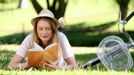 Pretty-girl-reading-beside-her-bike-in-the-park