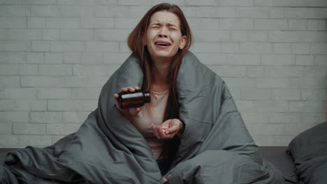 woman crying and taking medication in bed